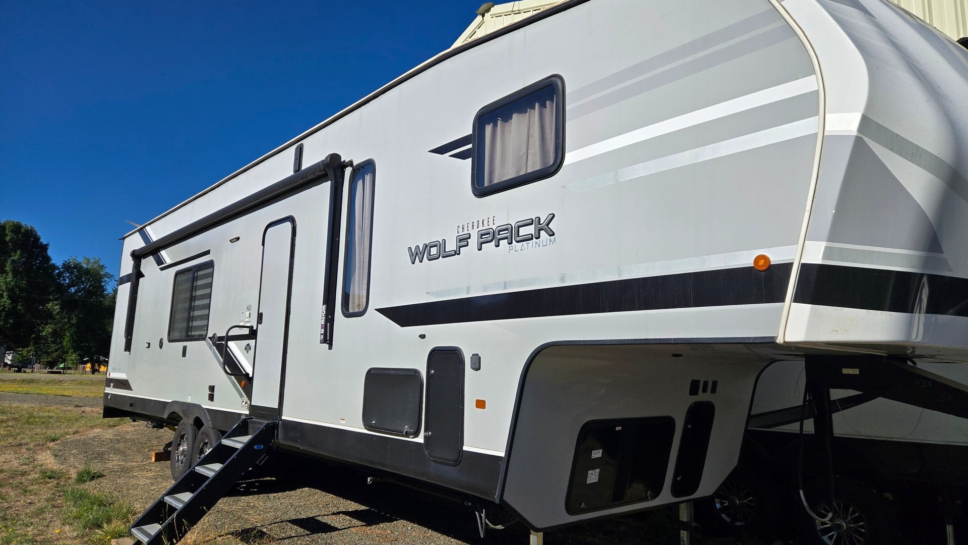 White Wolf Pack travel trailer RV parked on grass with blue sky in background