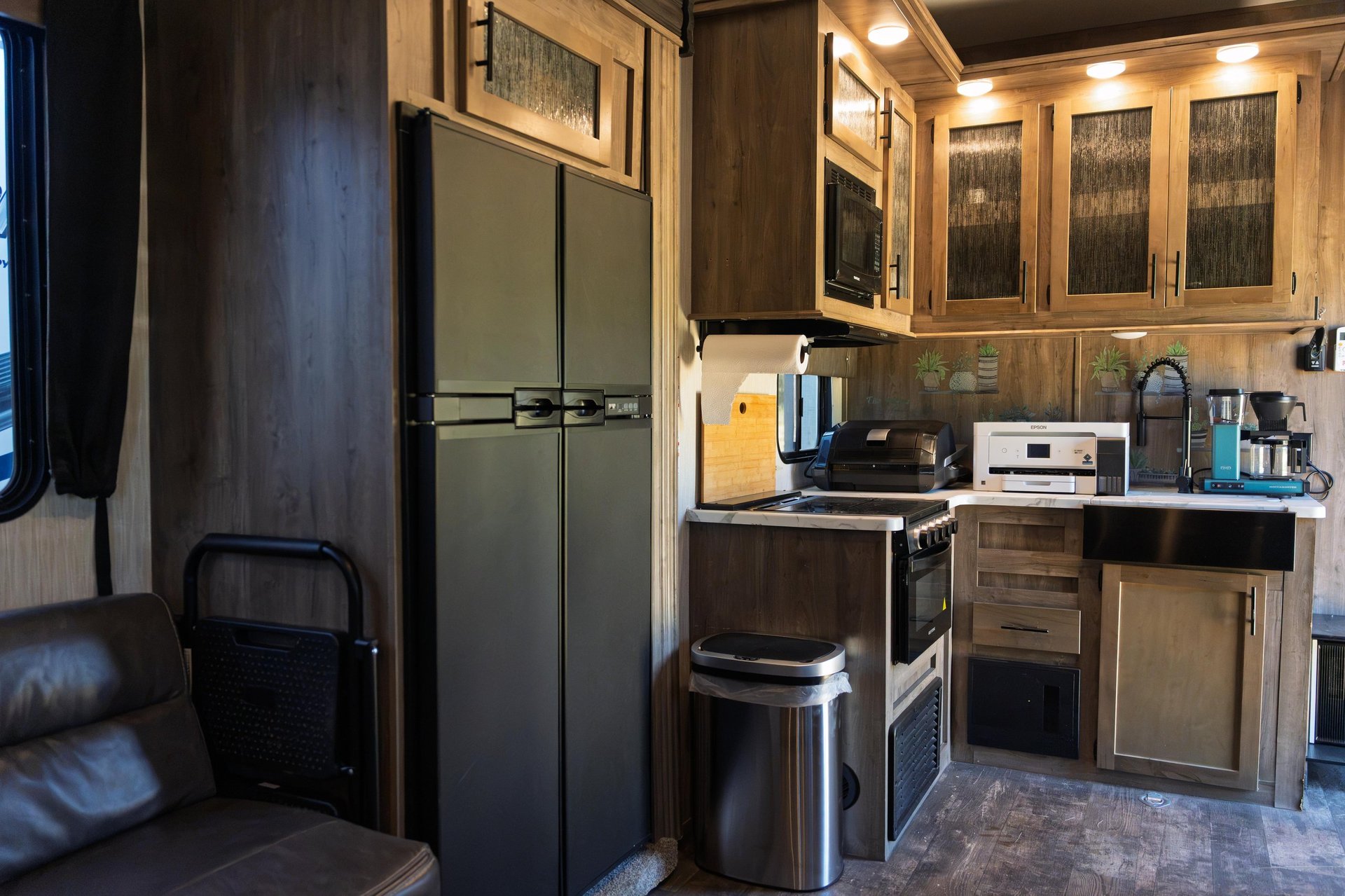 RV kitchen interior with stainless steel appliances, wooden cabinets, and compact cooking area